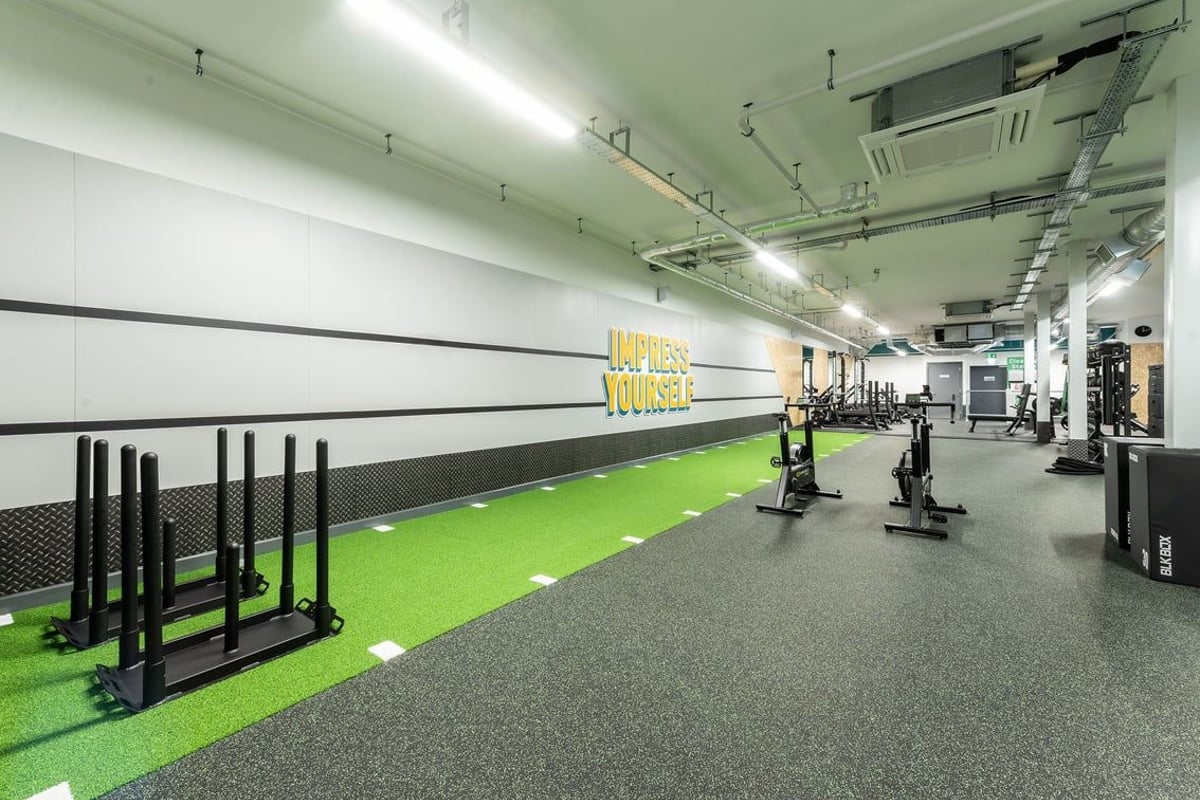 PureGym Macclesfield Silk Road: Gym studio with weight racks, turf area, free weights, and black rubber flooring.