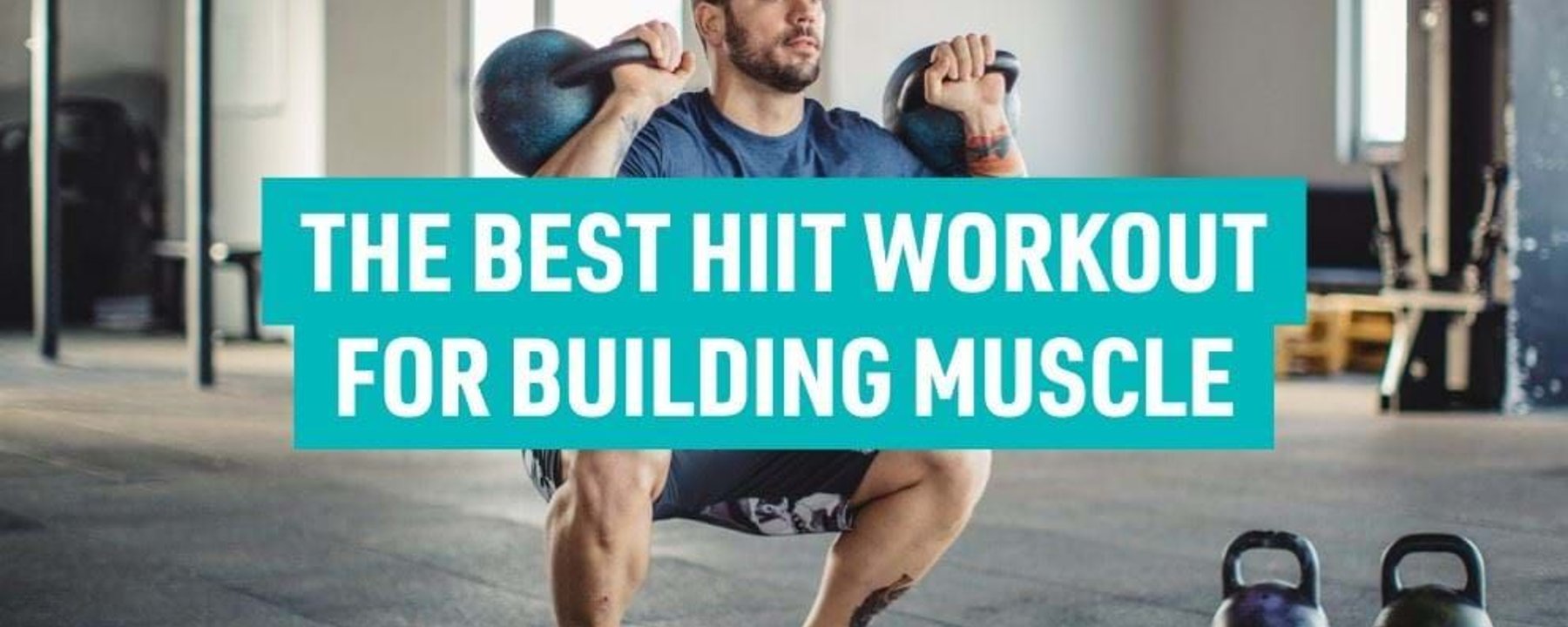 Man squatting with two kettlebells in a gym with two more kettlebells on the floor.