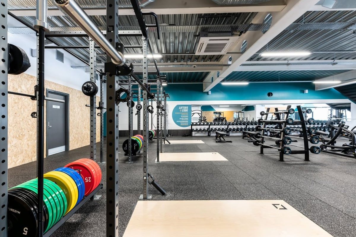PureGym Yate: Weight racks, colourful bumper plates, squat stands, and rubberised flooring in a gym.