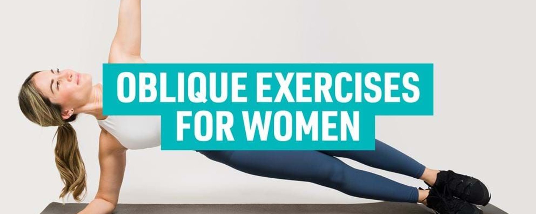 Woman in side plank position on exercise mat wearing sportswear and trainers