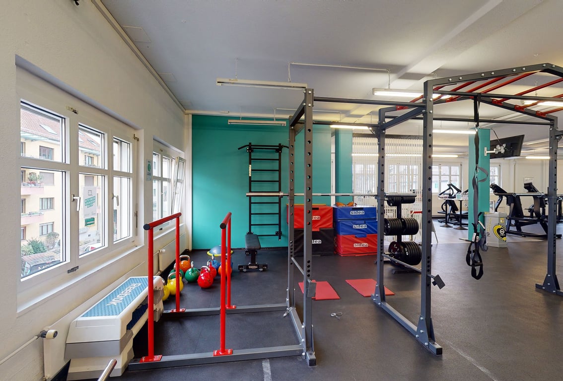 PureGym Zürich Oerlikon: Fitnessstudio mit Kraftgeräten, Freihanteln, gummiertem Boden und Klettergerüst.