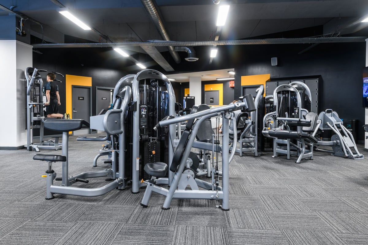 PureGym Bournemouth The Triangle: Rows of weightlifting machines, benches, and rubberized flooring in a dimly lit gym studio.