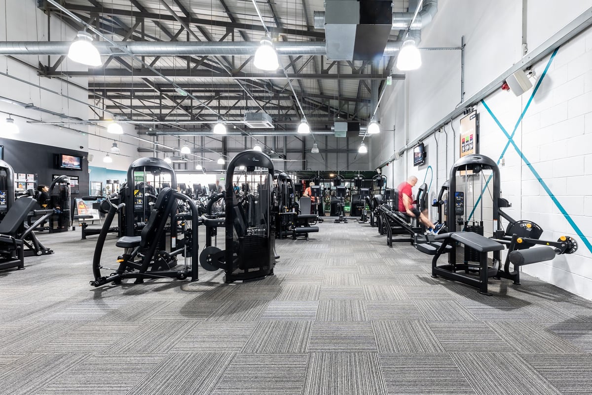 PureGym Wolverhampton Bentley Bridge: Rows of weight machines, benches, and rubberized flooring in a brightly lit gym space.