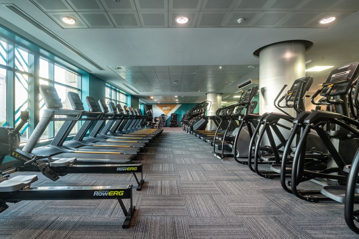 PureGym Edinburgh Exchange Crescent: Rows of treadmills and ellipticals in a bright fitness space with large windows.
