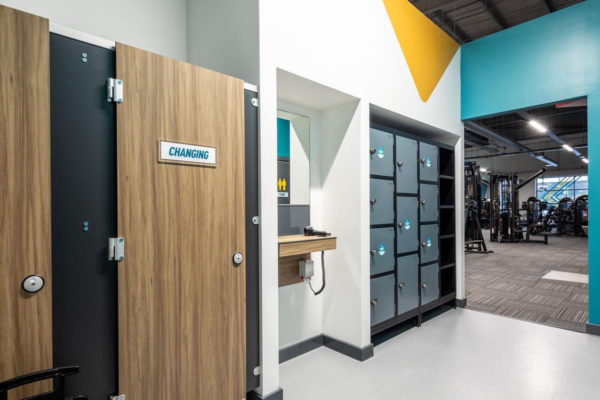 PureGym Wantage: Changing rooms with wooden lockers, benches, and cubicles.
