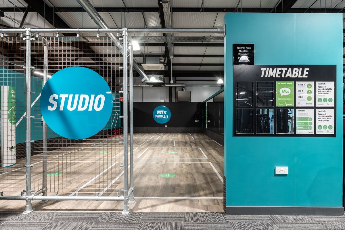 PureGym Kirkcaldy: Studio space with teal signage, wire mesh partition, and timetable display.