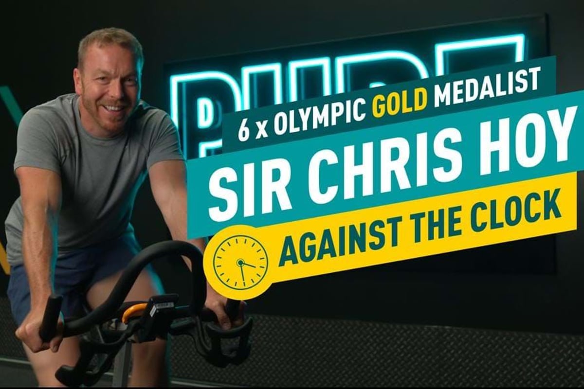 Man in grey t-shirt cycling indoors with text about Sir Chris Hoy and Olympic gold medals.