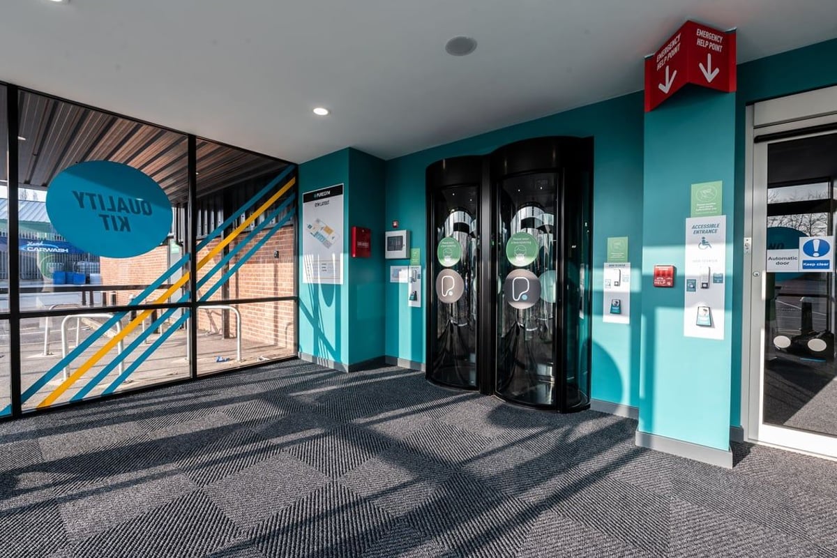 PureGym Swindon Stratton: Two turnstile entries with blue walls, signage indicating "Ytiligu Mv" space.