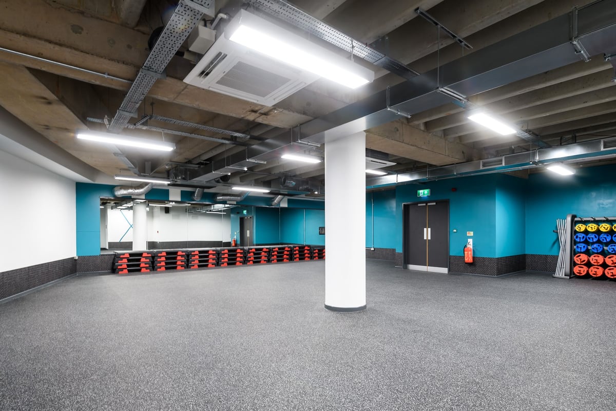 PureGym Birmingham Arcadian Centre: Rubberized flooring, weight plates and mirrored walls in a gym studio.