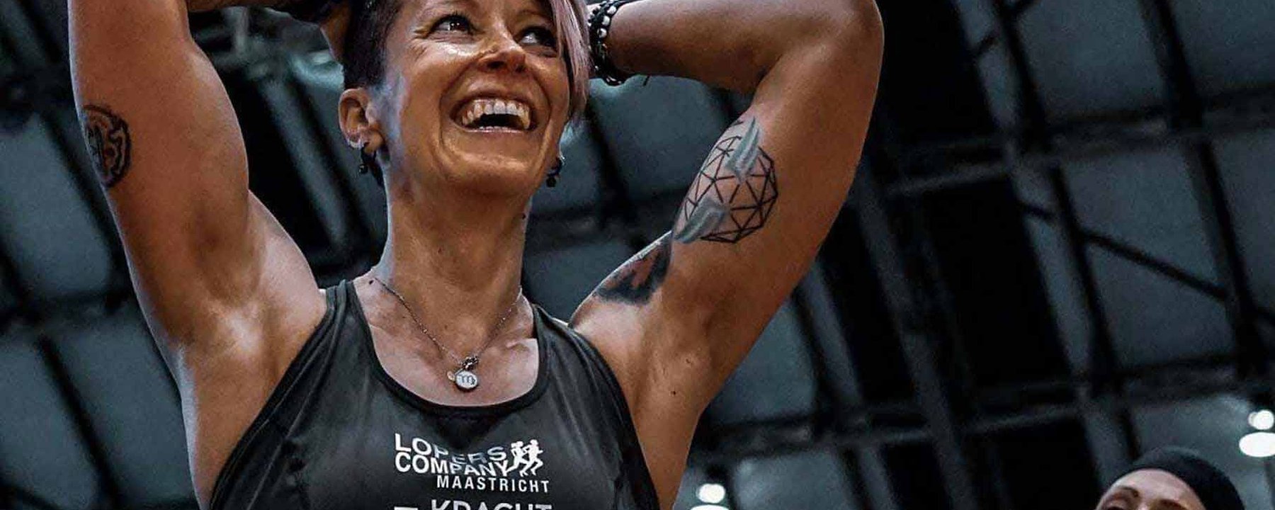 Deux femmes souriantes font de l'exercice sous un plafond haut éclairé