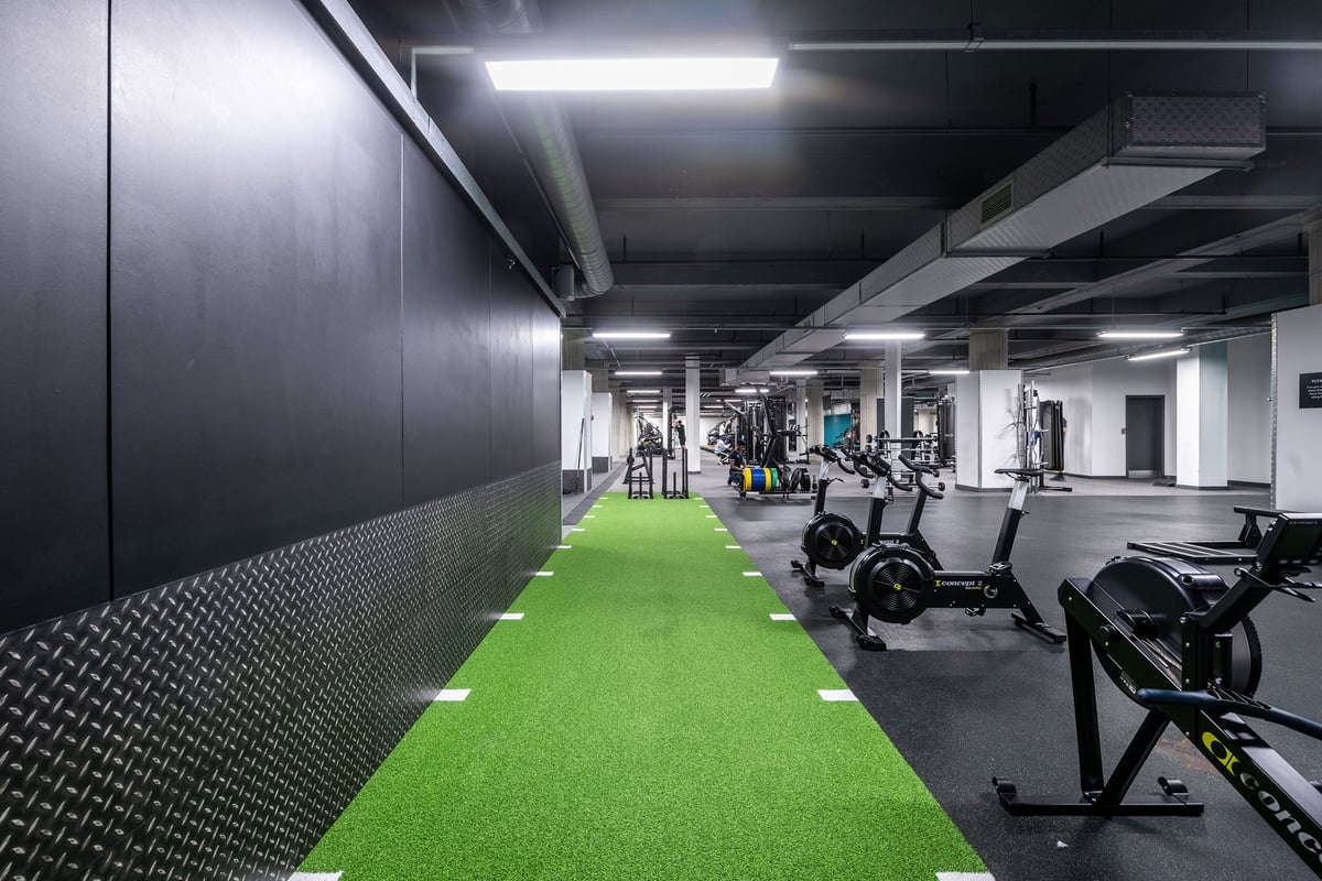 PureGym Liverpool Central: Weight racks, benches, green turf area, weights scattered in industrial basement gym.
