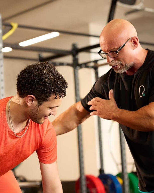 Personaltrainer bietet Einzelbetreuung für ein Mitglied in einer hell beleuchteten Fitnessstudio-Anlage