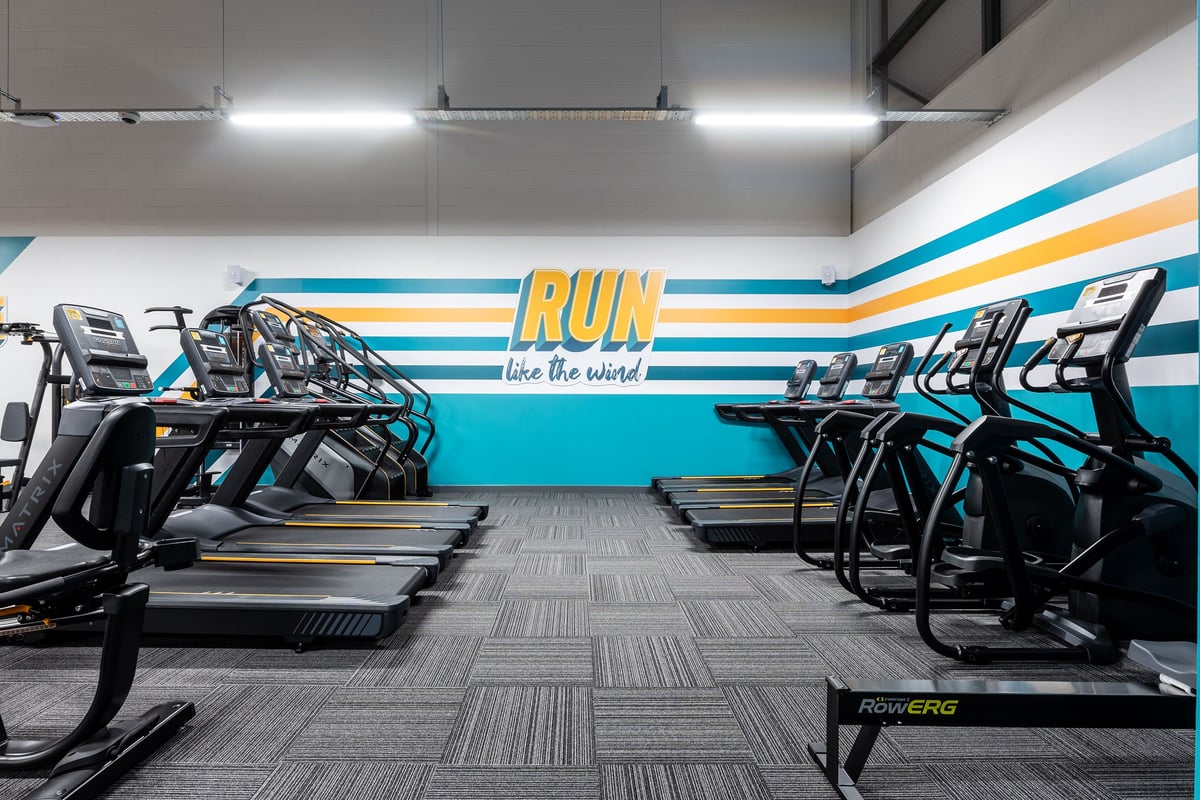 PureGym Harwich: Rows of treadmills and wall mural with "RUN like the wind" in a gym studio.