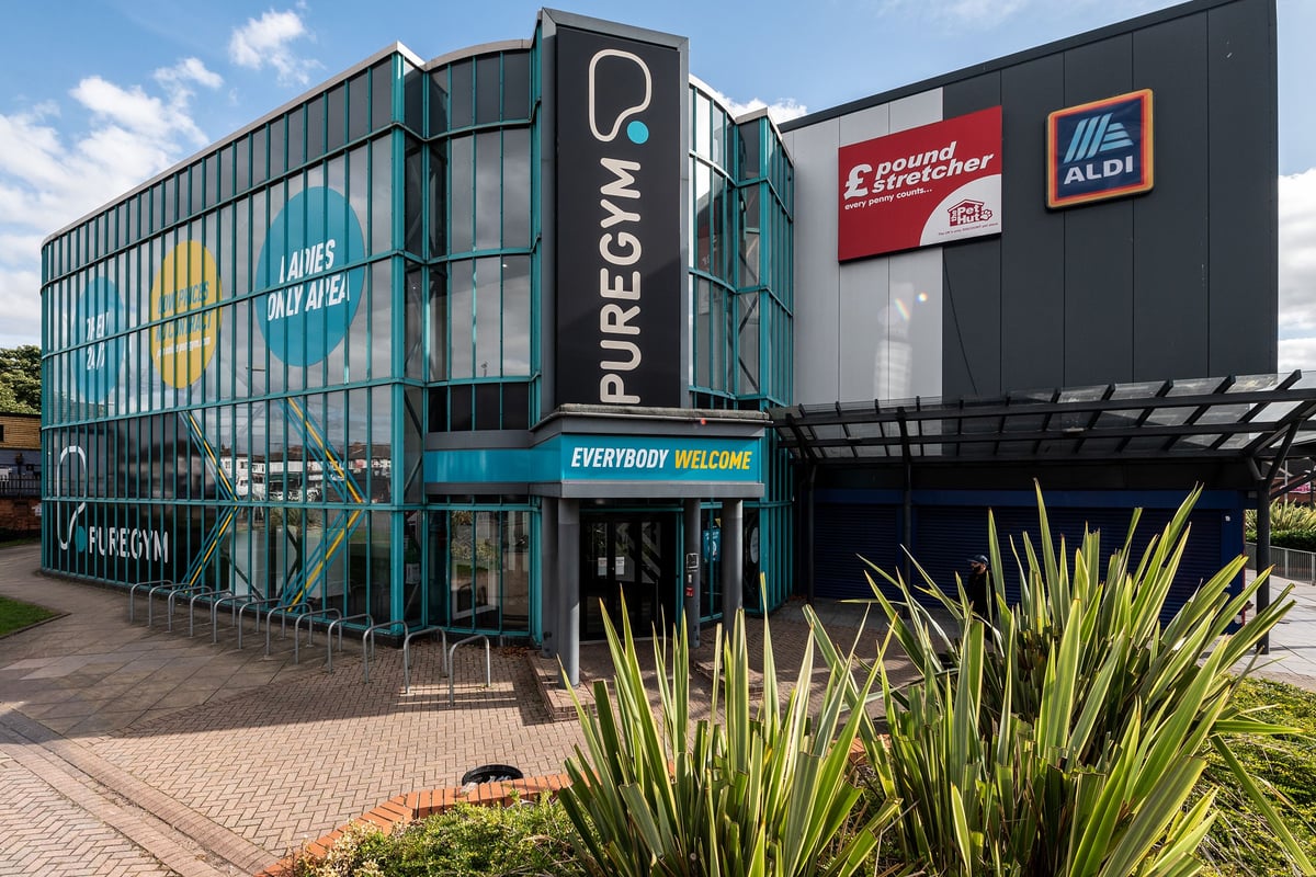 PureGym Birmingham Beaufort Park: Brightly-lit modern gym exterior with large branding, Aldi signage, and landscaping.