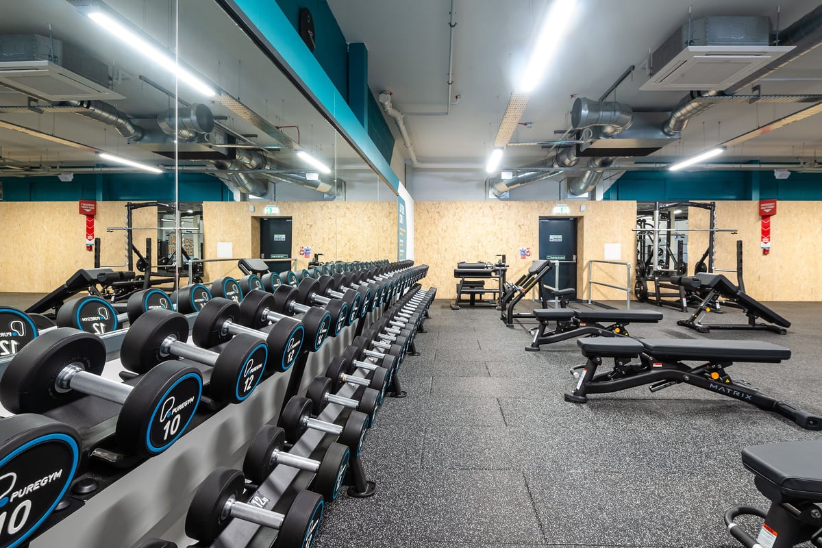 PureGym Linlithgow: Rows of stationary bikes, benches, free weights, and rubberised flooring in a gym.