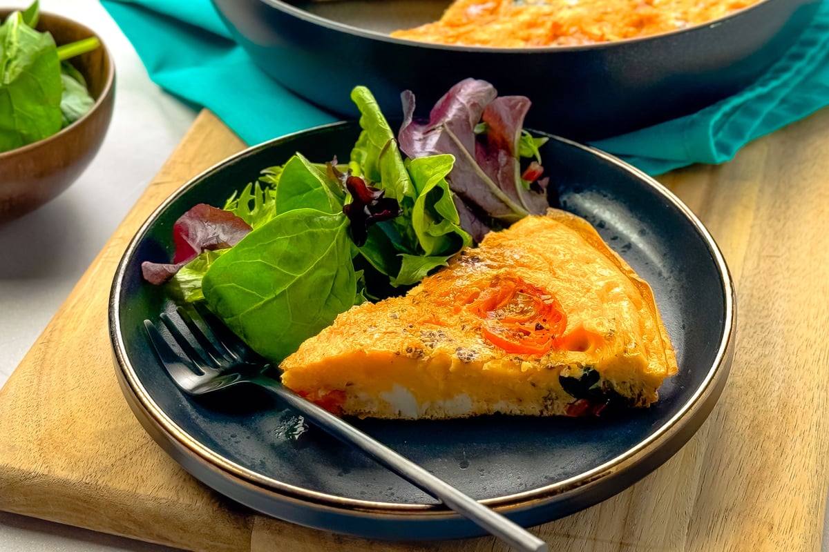 Slice of vegetable frittata with cherry tomatoes served with mixed salad leaves