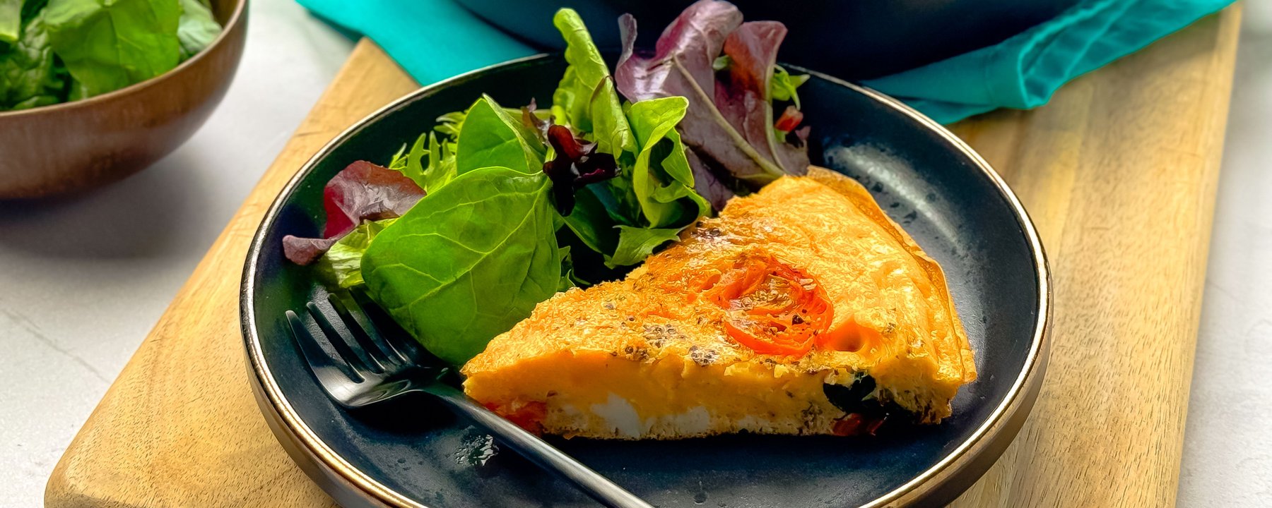 Slice of vegetable frittata with cherry tomatoes served with mixed salad leaves