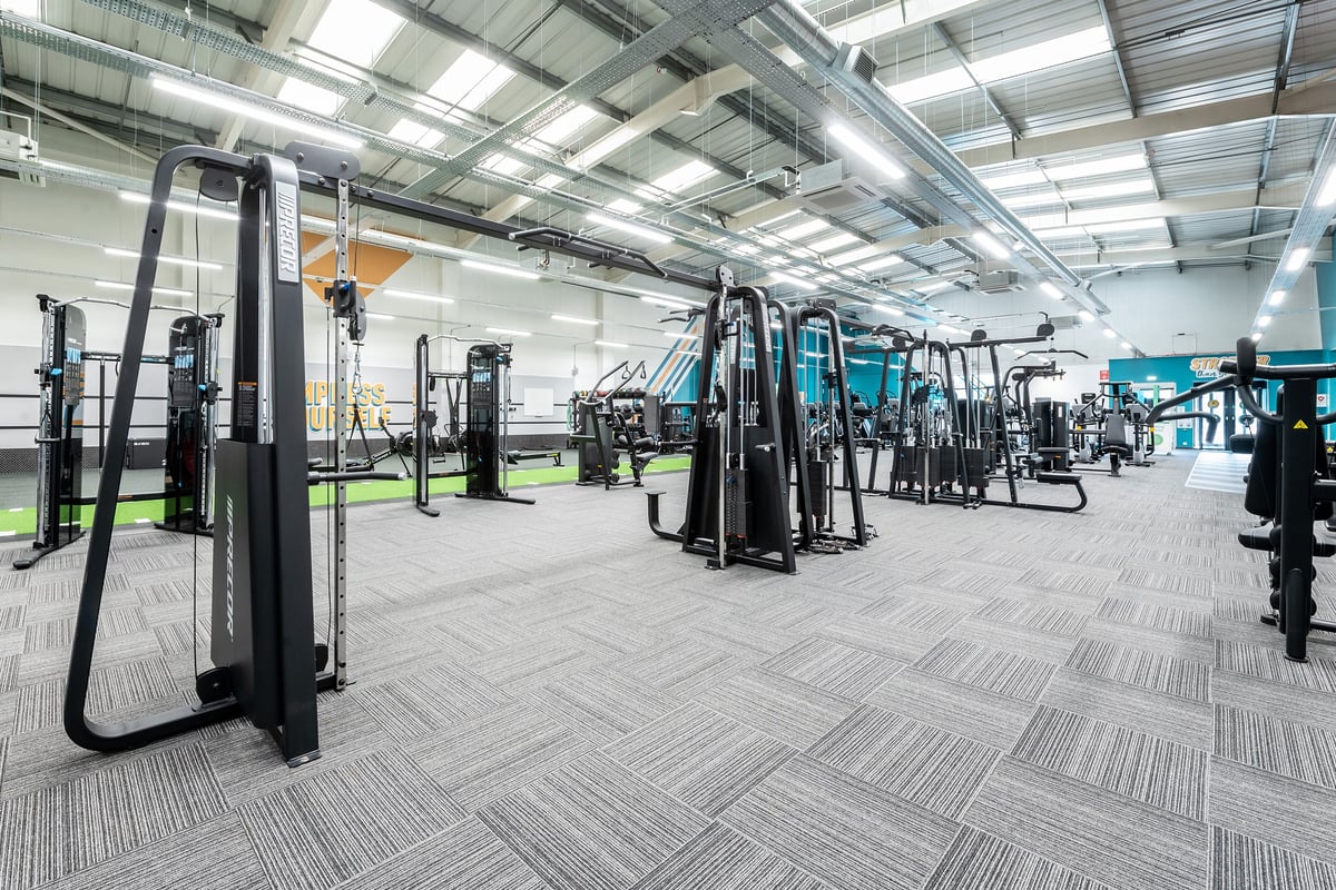 PureGym Ashford Warren Retail Park: Strength training area with resistance machines, cable columns, and rubberized flooring.