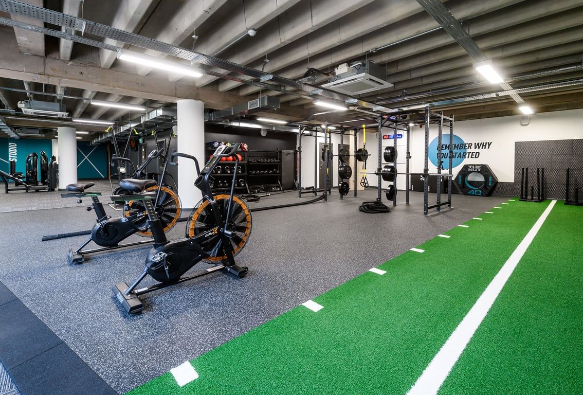 PureGym Birmingham Arcadian Centre: Gym studio with exercise bikes, resistance machines, turf area, and rubberized flooring.