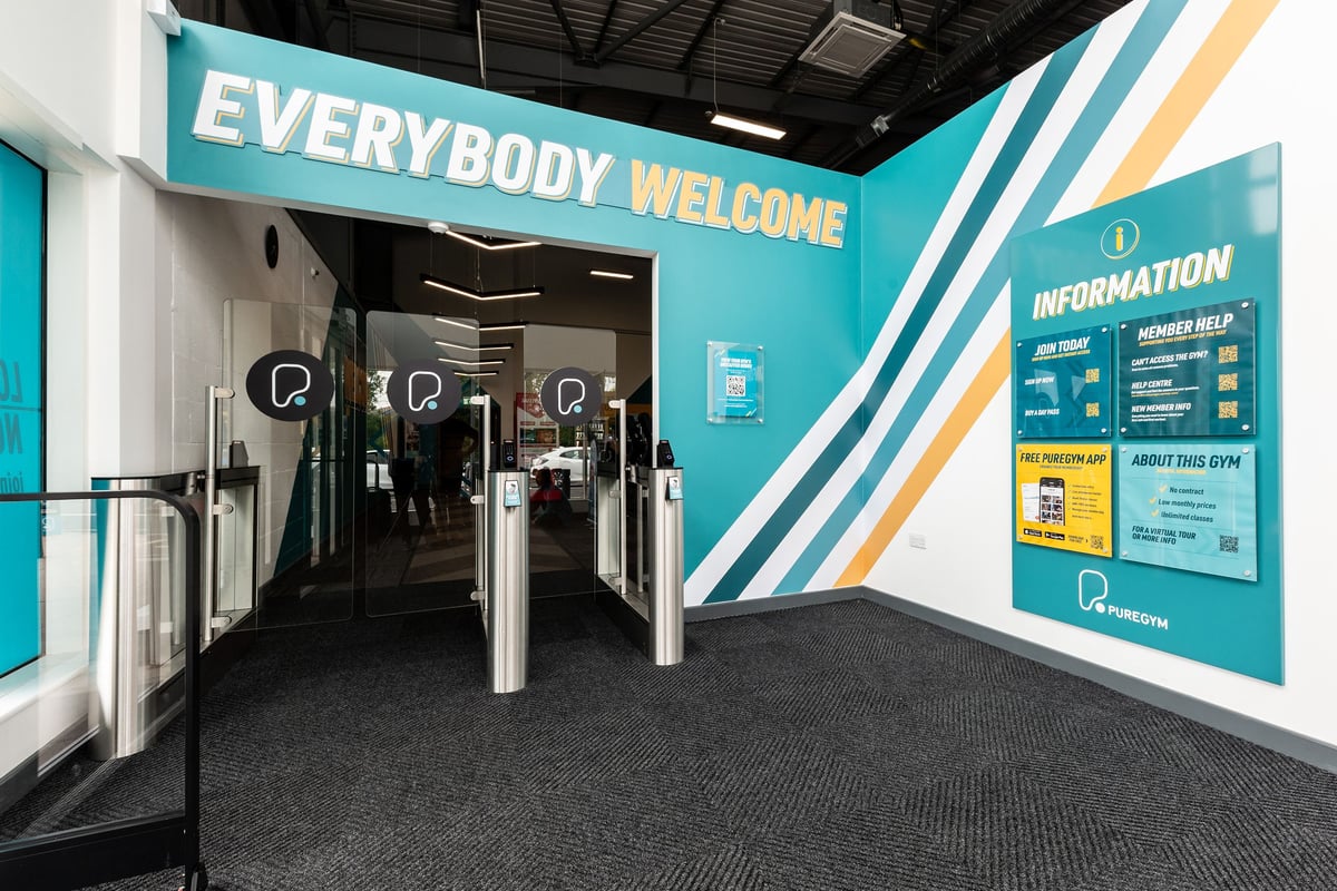 PureGym Tamworth: Entrance lobby with turnstiles, information signage, and "Everybody Welcome" greeting.