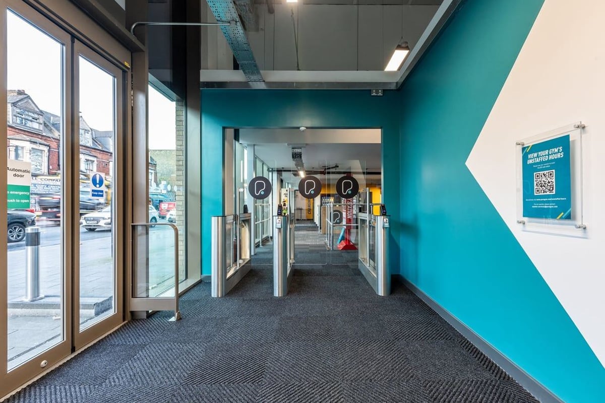 PureGym London Seven Sisters: Entry corridor with turnstiles, signage, and glass frontage onto street.