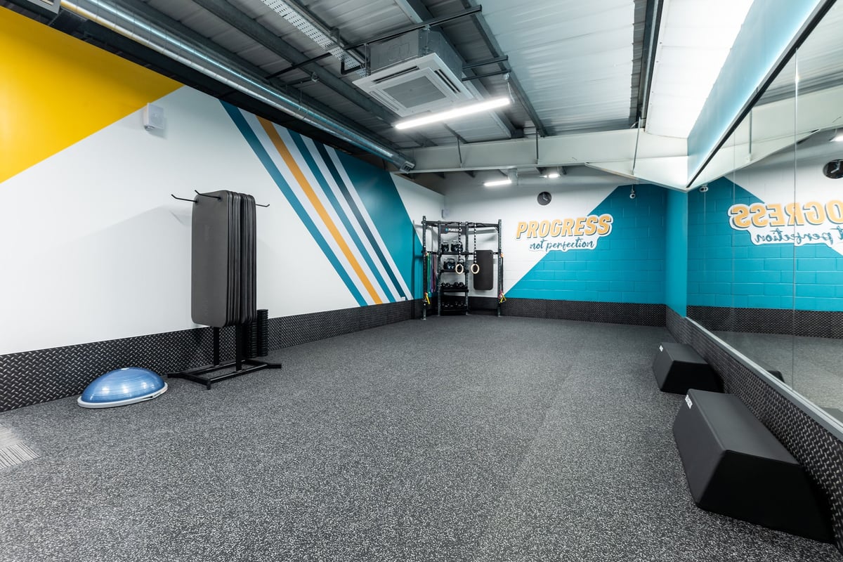 PureGym Shrewsbury Meole Brace: Turf area, various exercise equipment, benches and free weights, colourful wall graphics.