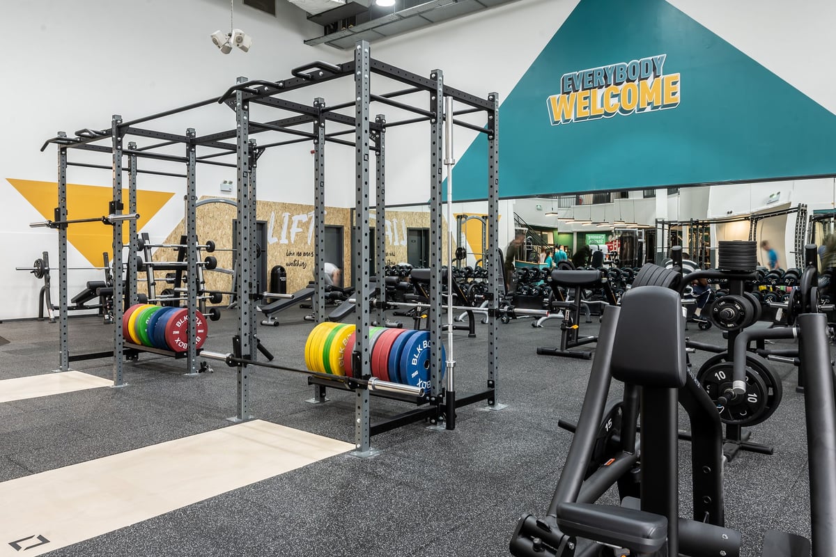 PureGym Rochdale: Squat racks, weight plates in multiple colours, rubberized flooring, and resistance machines.