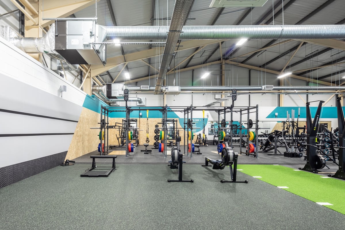 PureGym Neath: Functional training area with weightlifting rigs, freeweights, turf, and patio furniture.