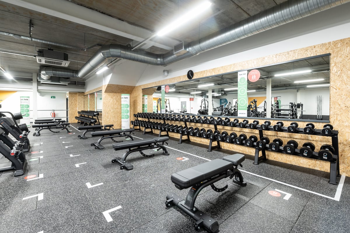 PureGym Plymouth Marsh Mills: Rows of weight benches, dumbbells, mirrors, and rubberised flooring in a weight room.
