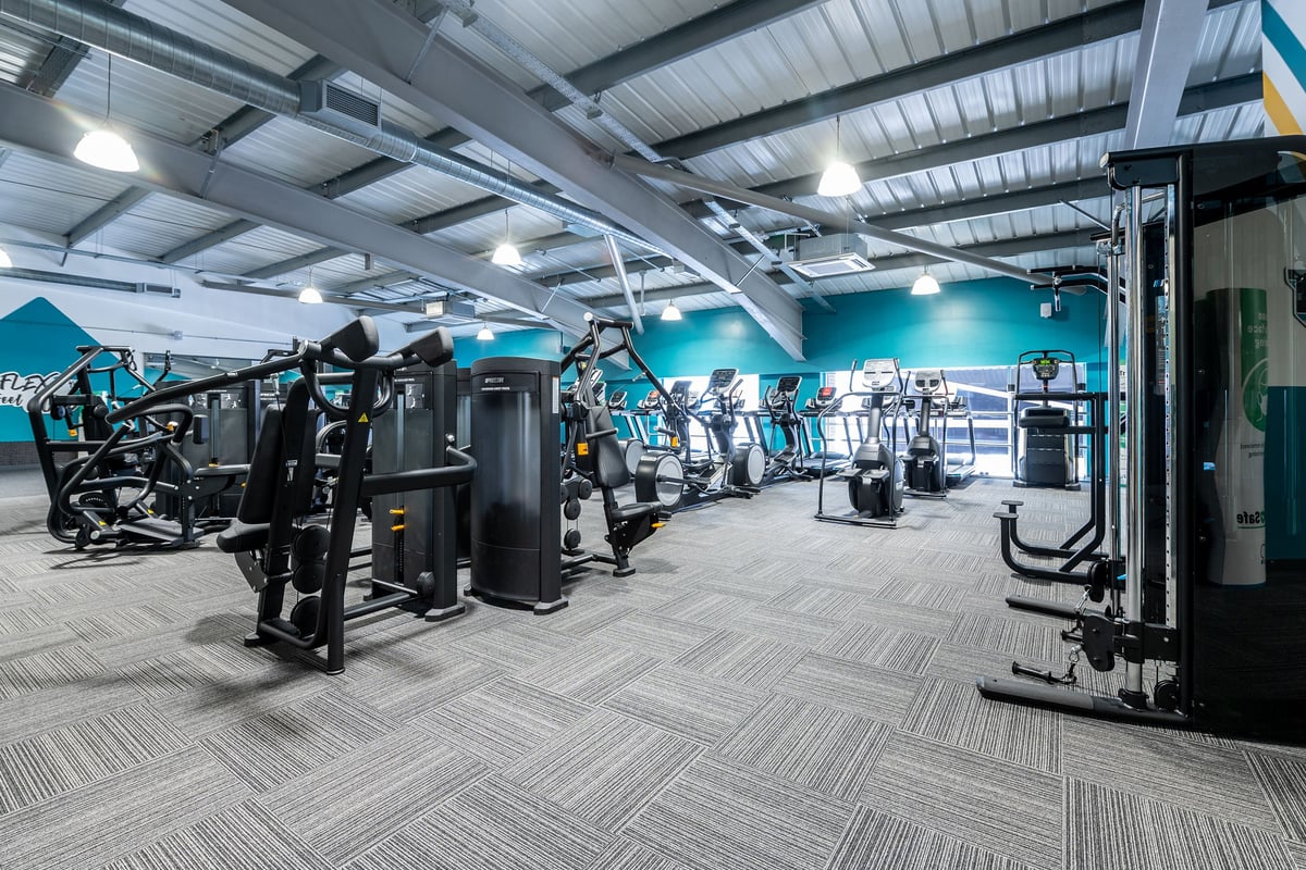 PureGym Bournemouth Mallard Road Retail Park: Rows of resistance machines in a teal-accented gym interior.