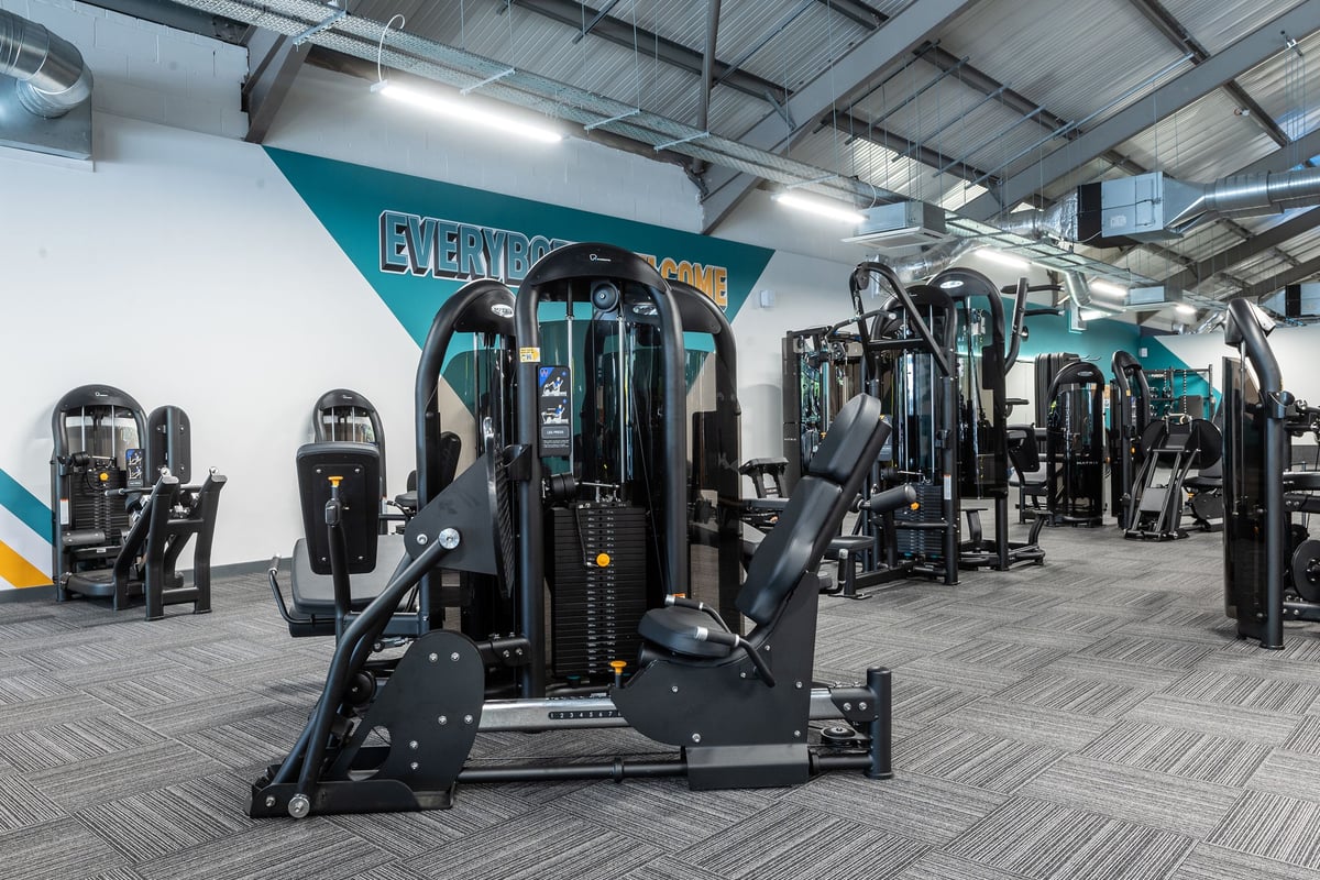 PureGym Derby Meteor Centre: Rows of weight machines, benches, and rubberized flooring in a bright workout space.