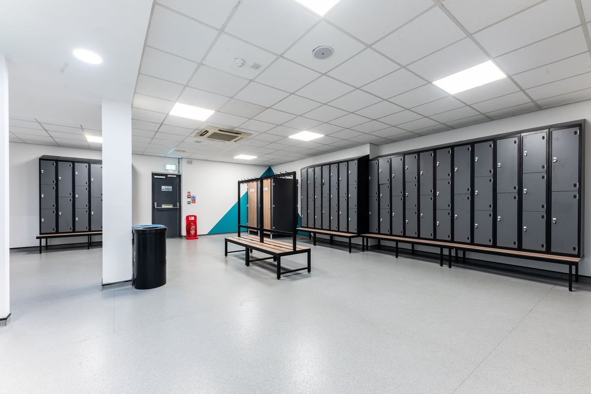 PureGym Purley: Rows of lockers, benches, and cubbies alongside an open floor space.