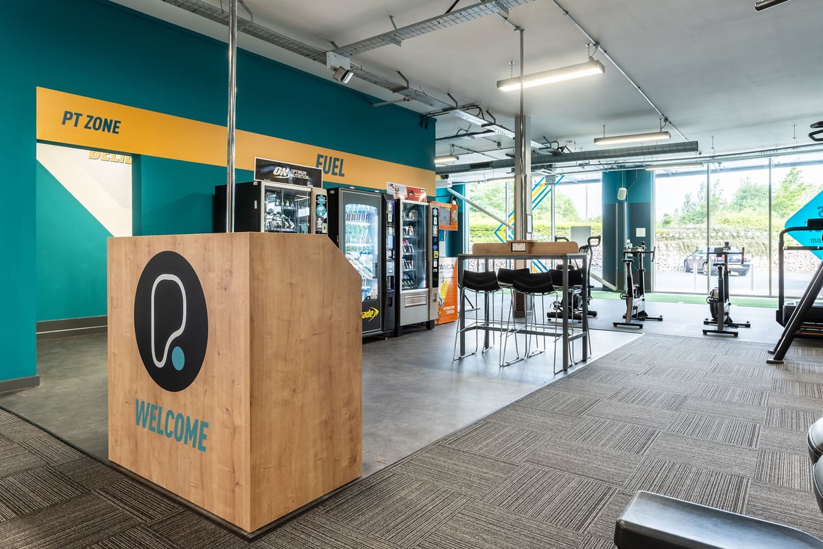 PureGym Wirral Bidston Moss: Cardio machines, vending kiosks, seating areas, and exercise equipment in an open fitness space.