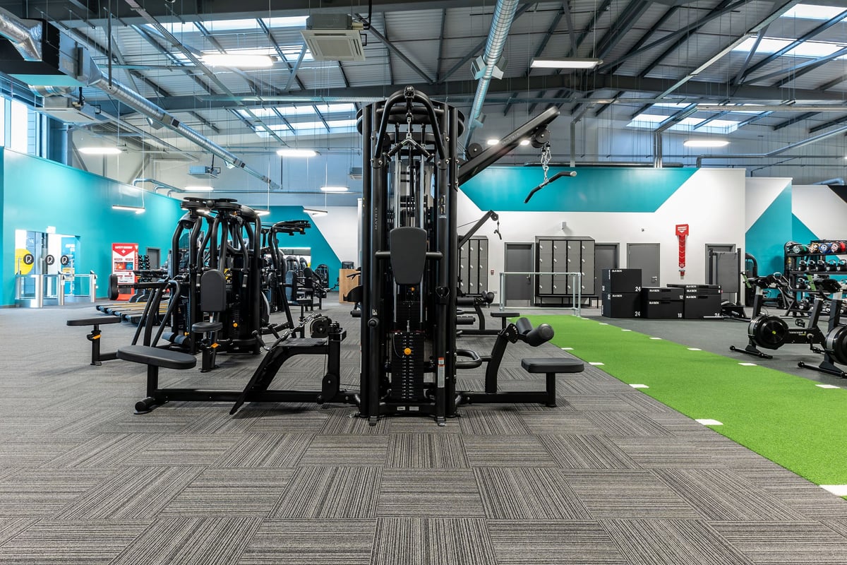 PureGym Kirkby: Gym interior with cable machines, free weights, weight racks, turf area, and industrial decor.