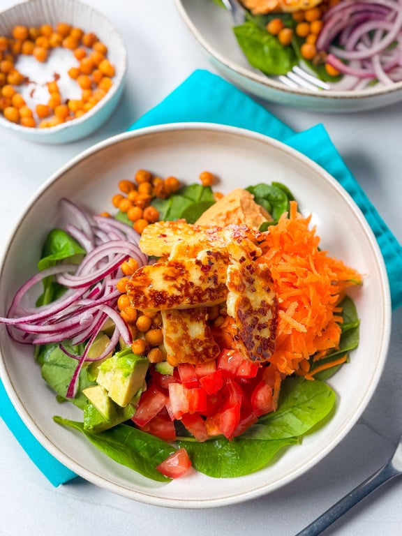 Salad bowl with grilled halloumi, spinach, shredded carrot, tomato, avocado, red onion
