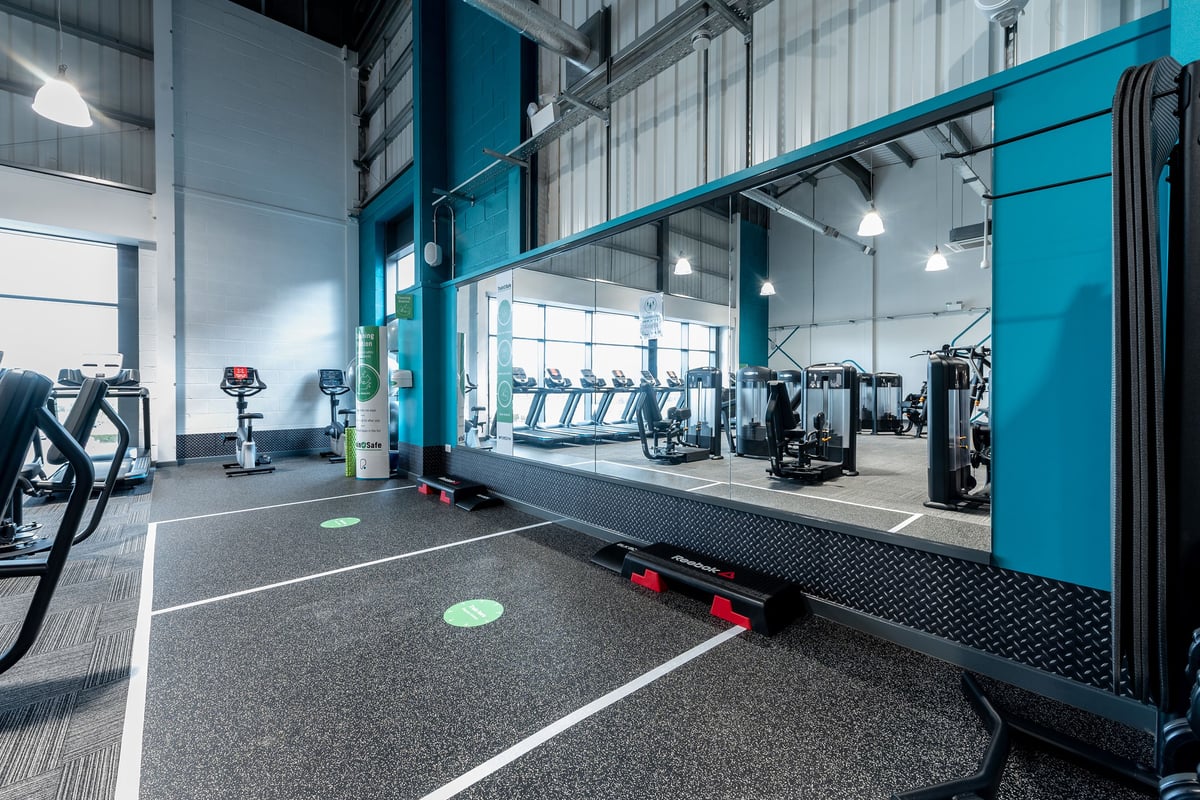 PureGym Birmingham Longbridge: Strength racks, rubberized turf, weightlifting platforms, and mirrors lining the gym interior.
