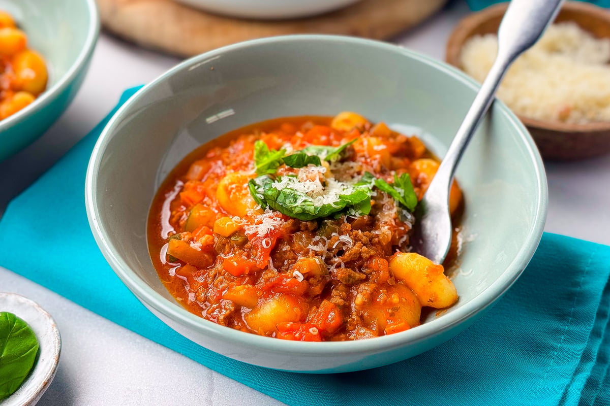 Gnocchi in tomato-based sauce with mince, garnished with herbs and grated cheese