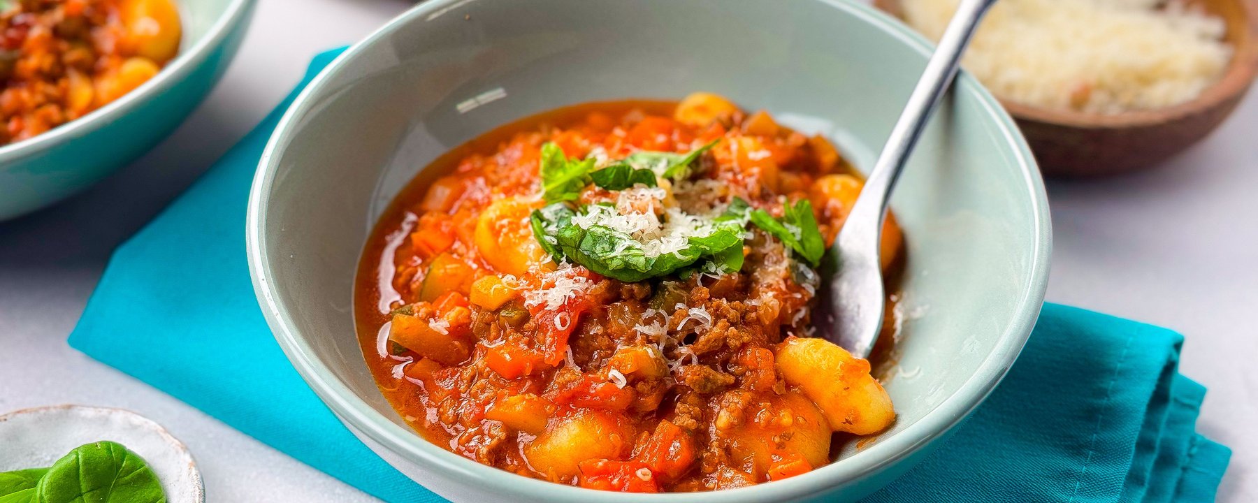 Gnocchi in tomato-based sauce with mince, garnished with herbs and grated cheese