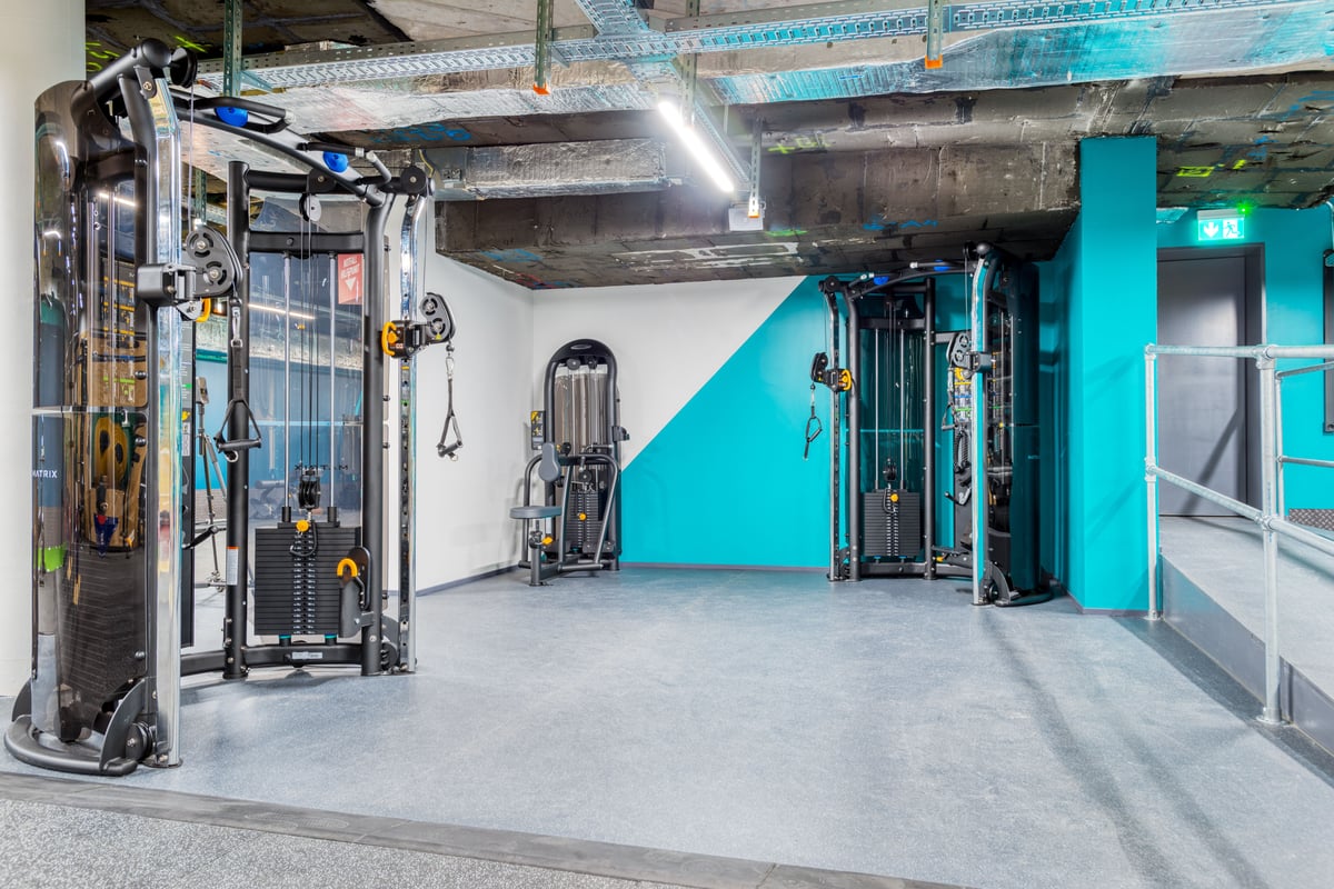 Une section de la gym avec plusieurs machines à câbles et de musculation fonctionnelle