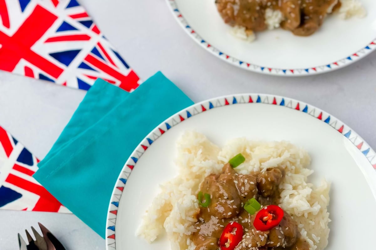 Two plates of rice with meat in sauce garnished with red chili and spring onions