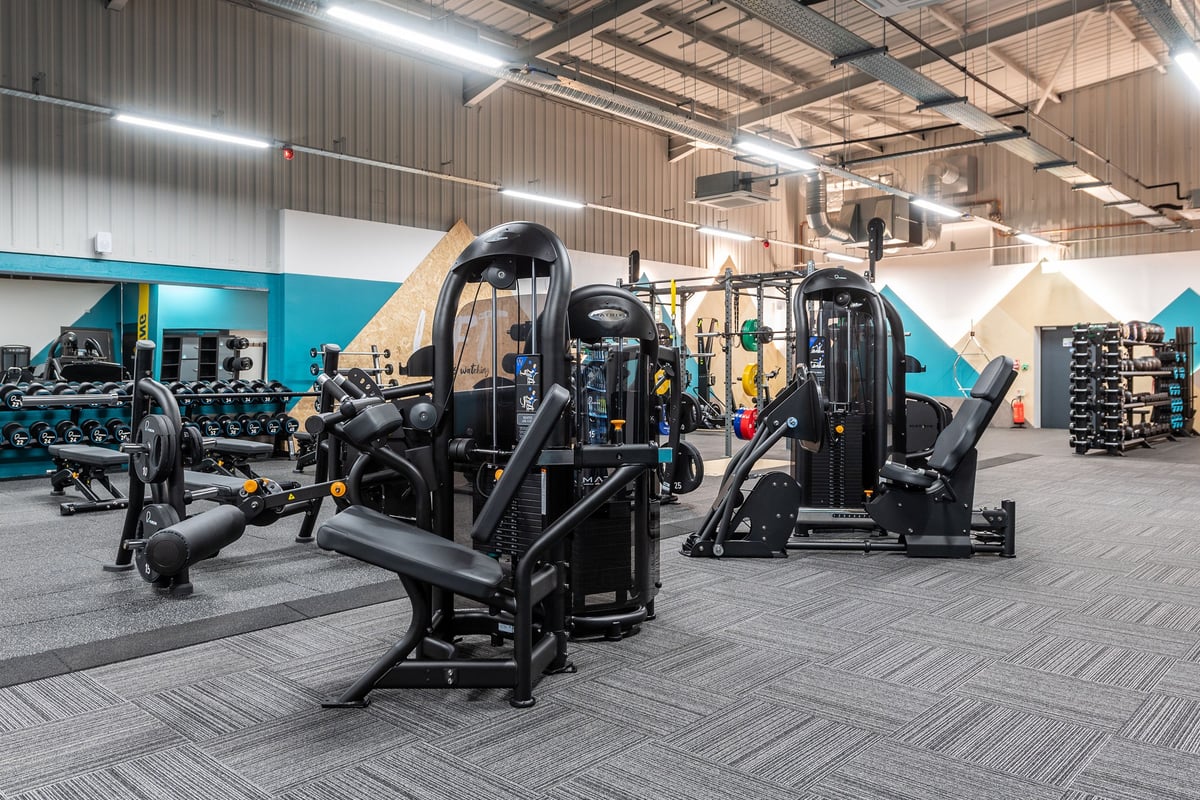 PureGym Alfreton: Rows of weight machines, benches, and free weights on rubberized flooring inside a gym.