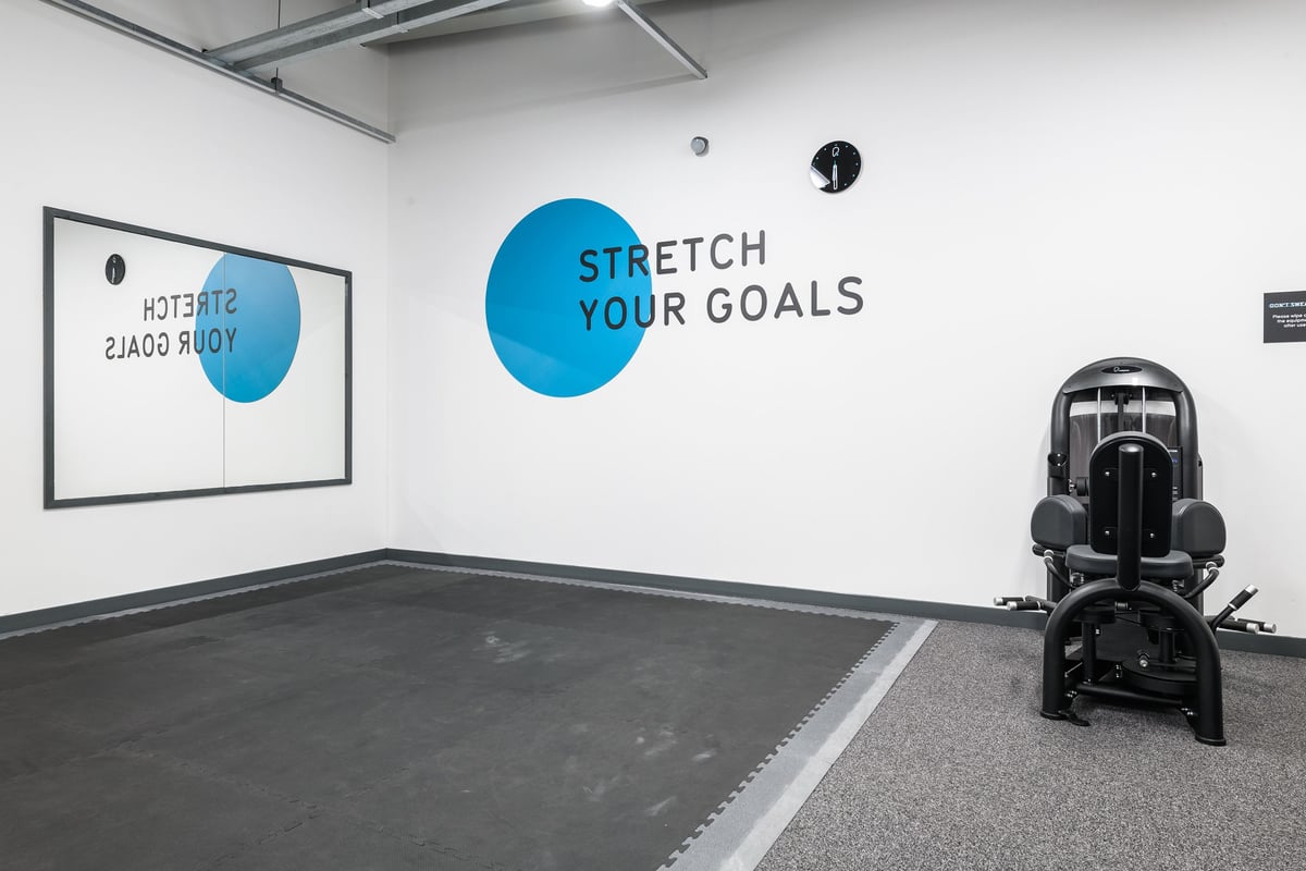 PureGym Aberdeen Wellington Circle: Stretch equipment on rubberized floor, wall motivational text, and framed artwork.