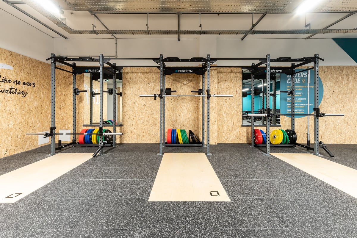 PureGym London Crouch End: Weightlifting rig frames, colourful weight plates, rubberized floors, OSB walls.