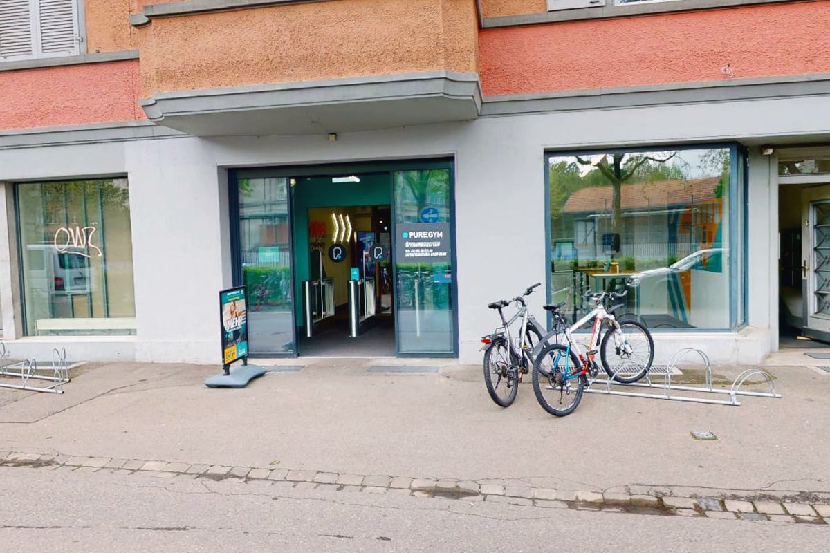 PureGym Bern Lorraine: Extérieur d'un bâtiment avec des vélos garés à l'extérieur et une entrée avec portes automatiques.
