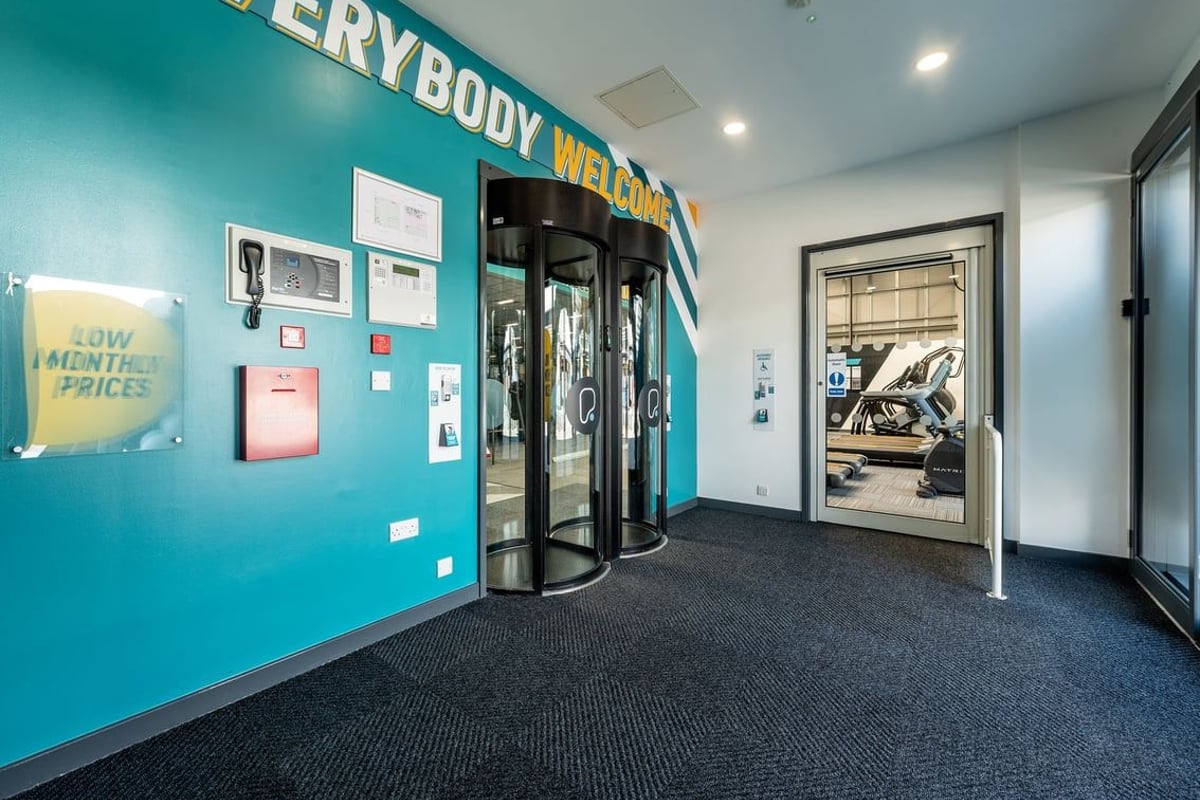 PureGym Coventry Warwickshire Shopping Park: Entrance area with glass revolving door and teal accent wall.