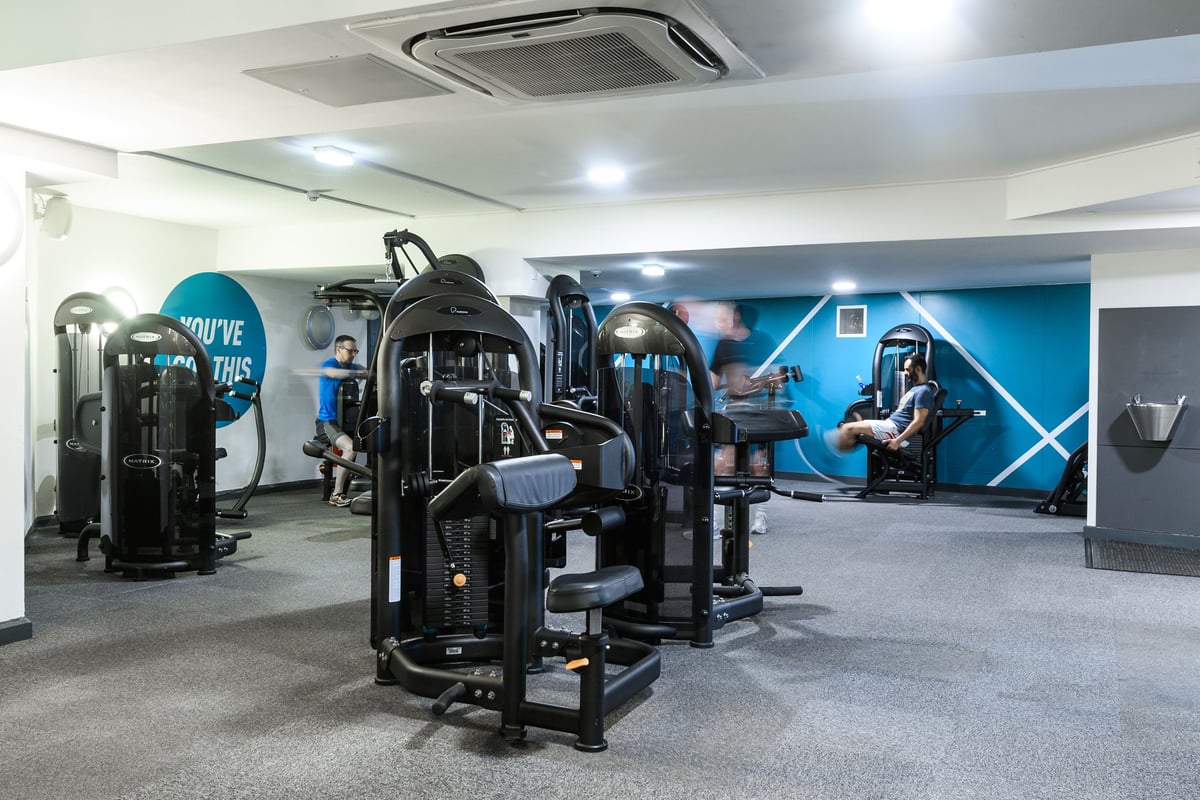 PureGym London St Pauls: Rows of strength training machines, free weights, mirrored walls, and blue branded accent walls.