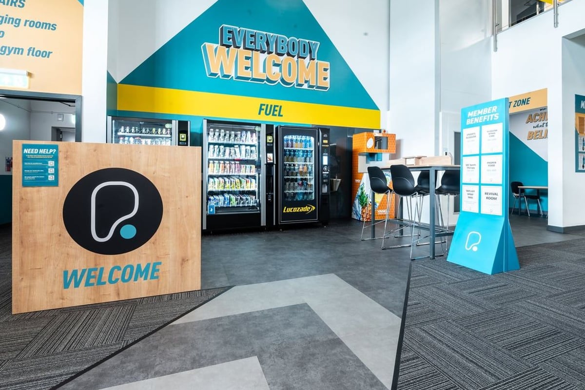 PureGym Glasgow Rutherglen: Welcome area with vending machines, seating, and signage promoting fuel and refreshments.