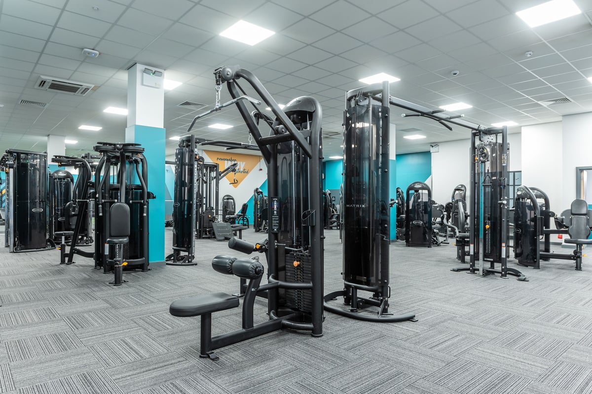 PureGym London Ilford: Weight machines, benches, and mirrored walls in a commercial fitness studio.