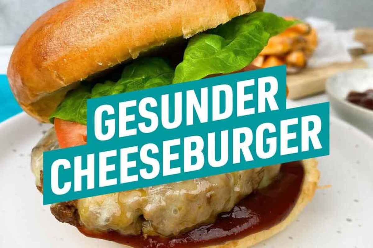 Cheeseburger mit Salat, Tomate, geschmolzenem Käse und Sauce auf weißem Teller