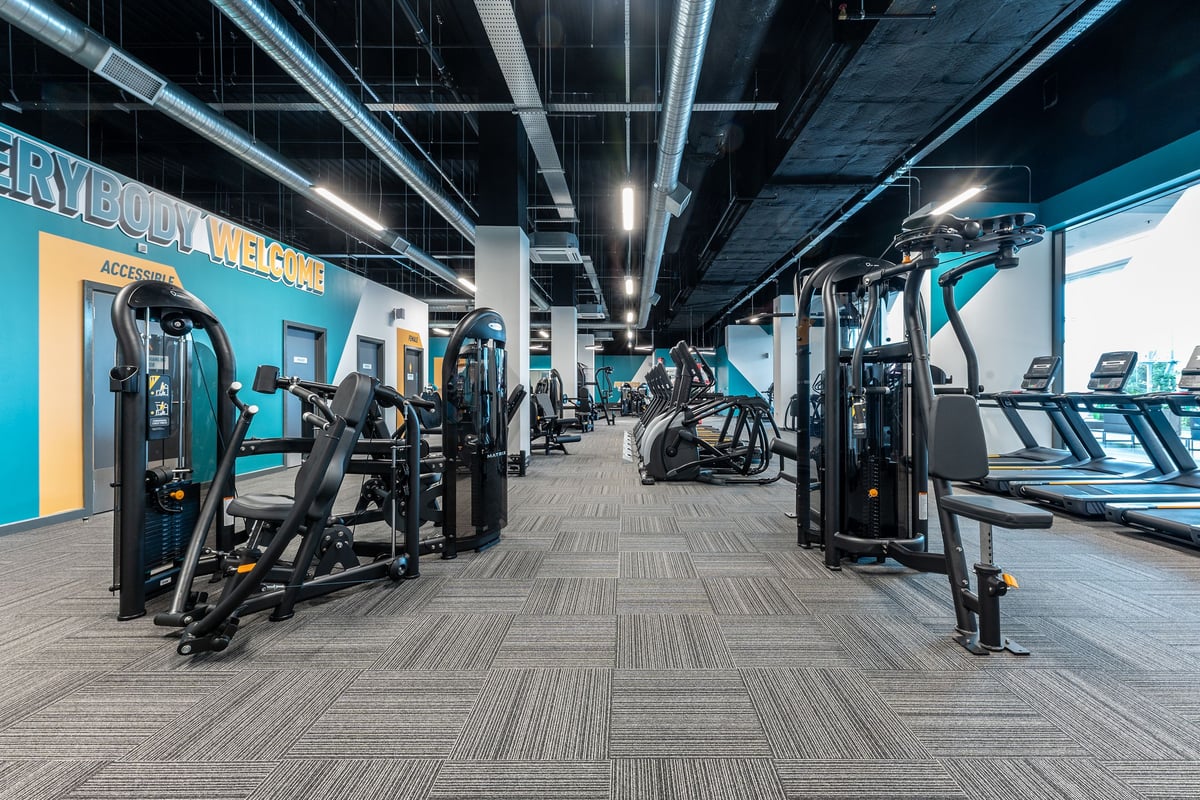 PureGym Hatfield: Resistance machines, weight stations, cardio equipment in a dimly lit fitness centre.